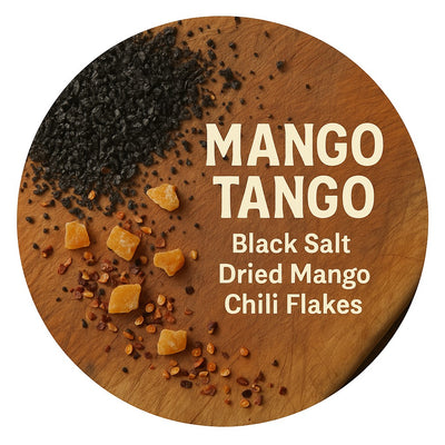 Round wooden board with black salt, dried mango, and chili flakes labeled 'Mango Tango'.